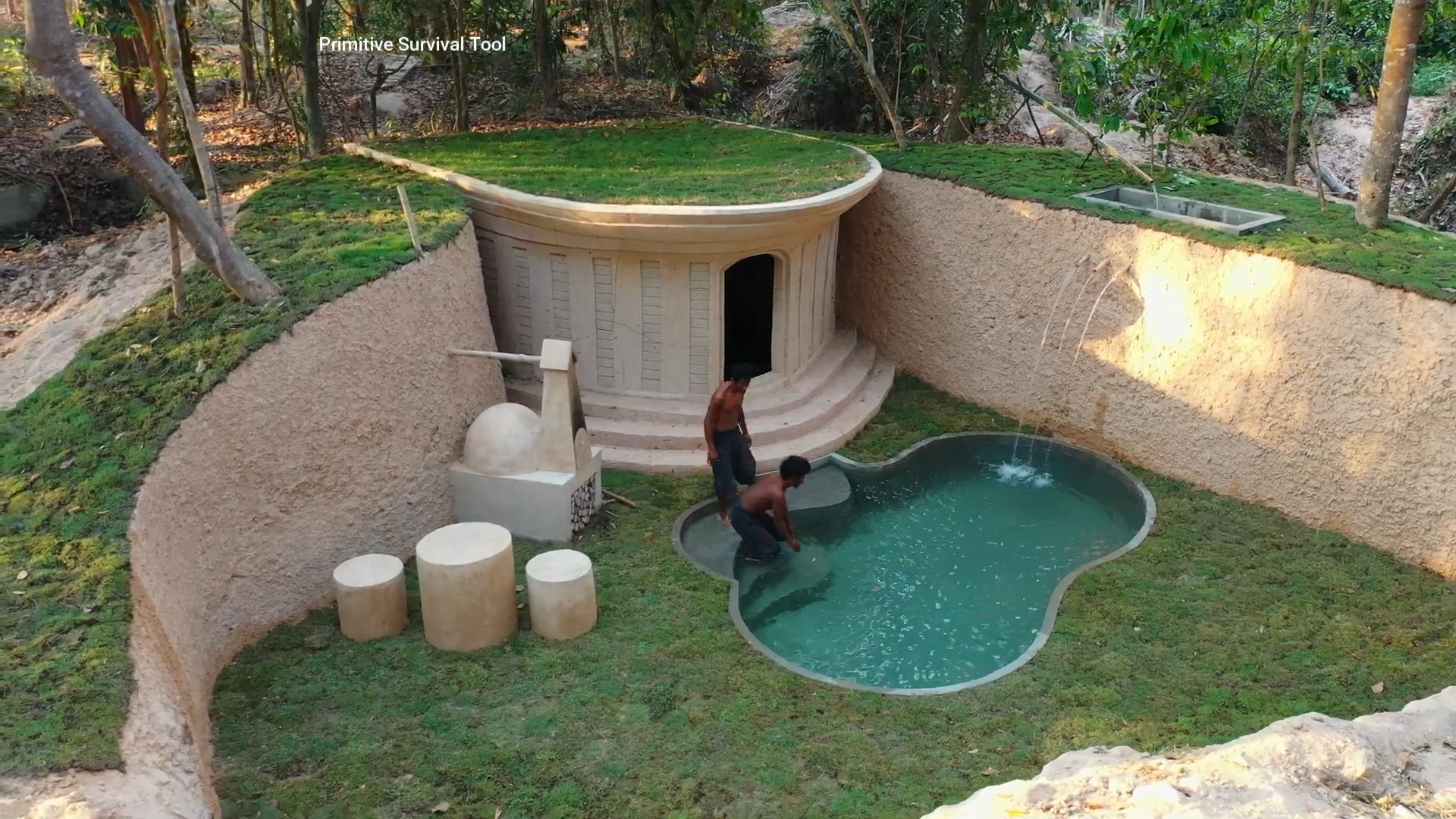 Two men build a hidden underground hut with a grass roof and pool