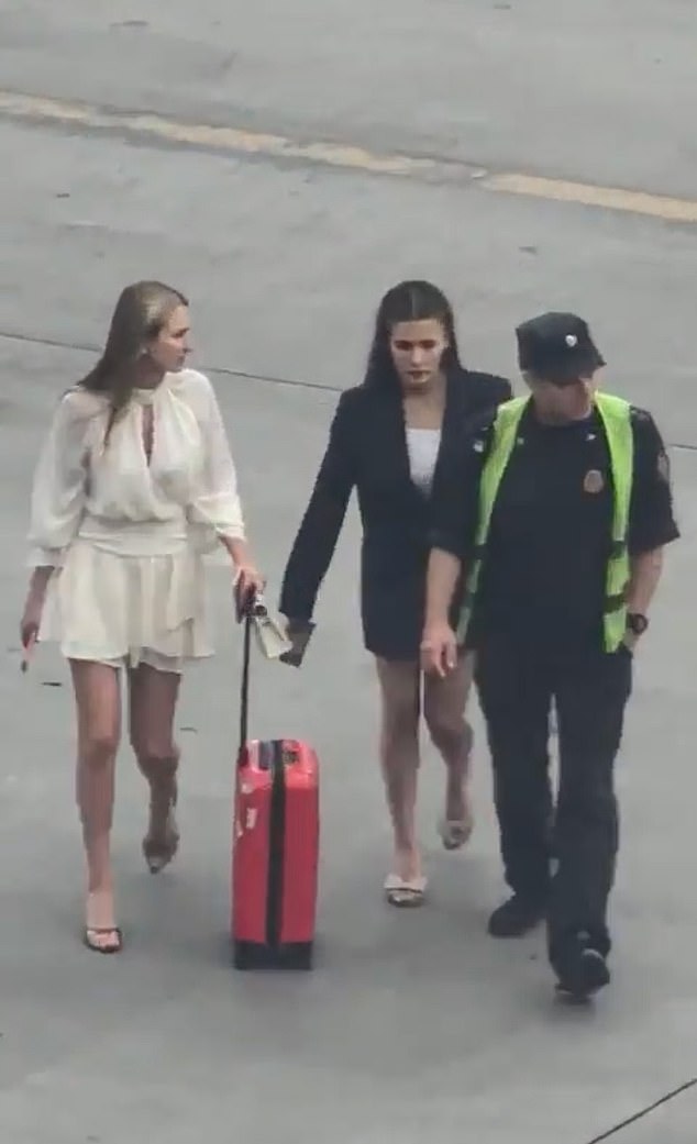 Dragging their luggage behind them, the pair can be seen waving frantically towards the cockpit in an apparent attempt to persuade the pilot to stop