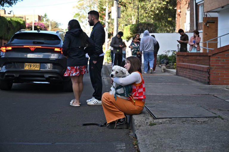 A woman carrying her dog evacuates after an earthquake in Bogota