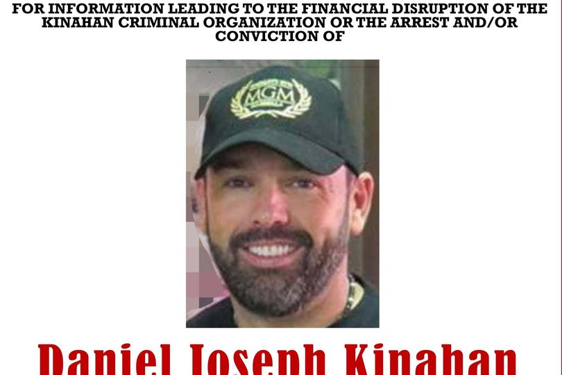 An official document features a photograph of an individual wearing a black t-shirt and a green baseball cap with white text. Below the photograph, the name 