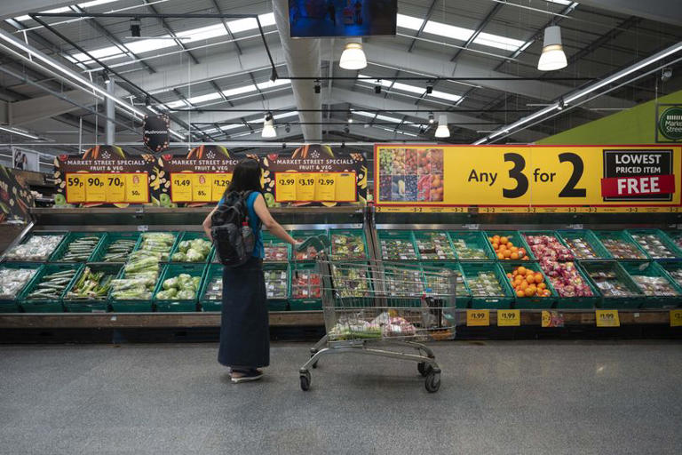 A woman shops at a UK supermarket in the fruit and veg aisle