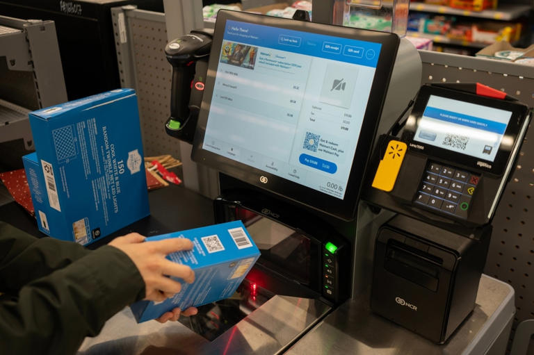 Customer scanning a boxed product at a Walmart self-checkout kiosk.