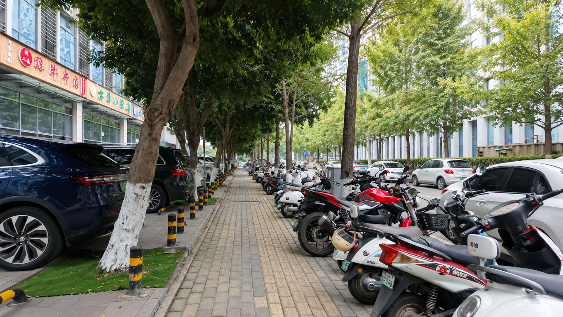 En smal trottoar mellan bilar och rader av elsparkcyklar