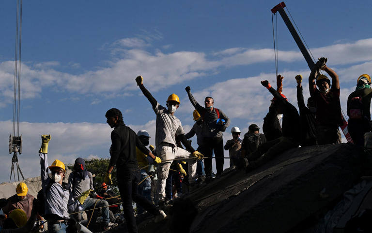 Volunteers search for survivors amid the rubble of a collapsed building in Cali - JOAQUIN SARMIENTO/AFP