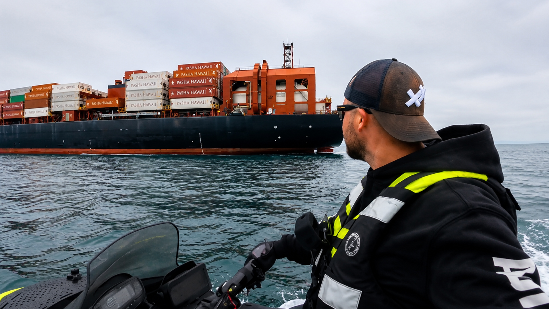 Small jet ski passes a giant cargo ship offshore