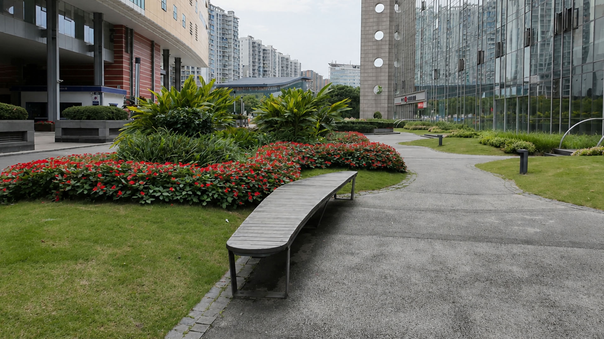Modern office garden features curved bench and vibrant red flower beds