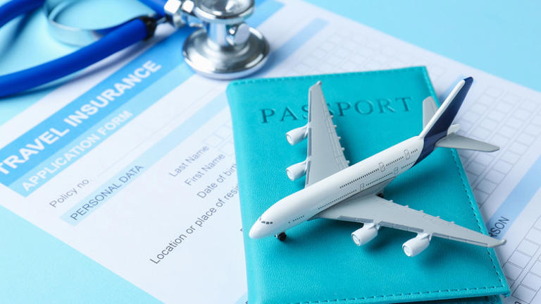 Travel insurance application form, stethoscope, passport, and plane model on light blue background