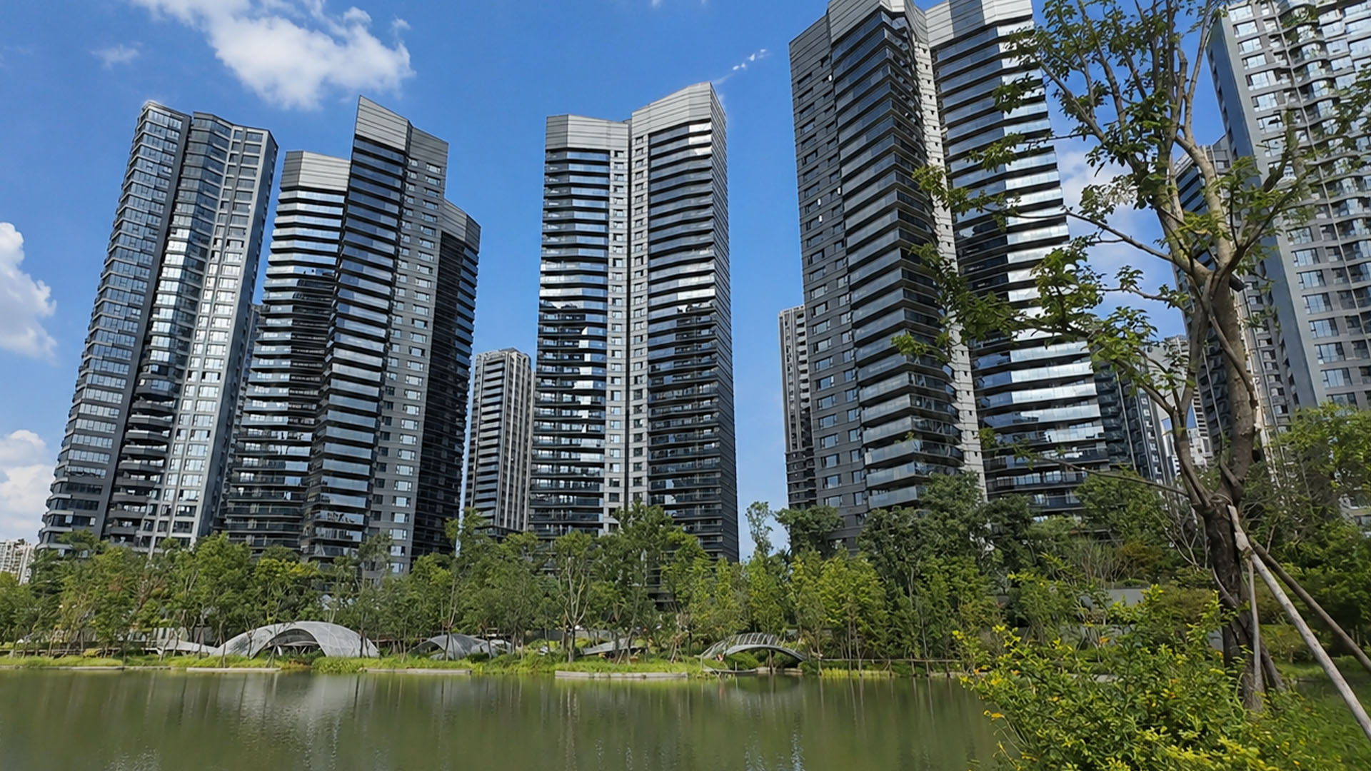 Contemporary residential skyline reflects across calm lake beneath blue ...