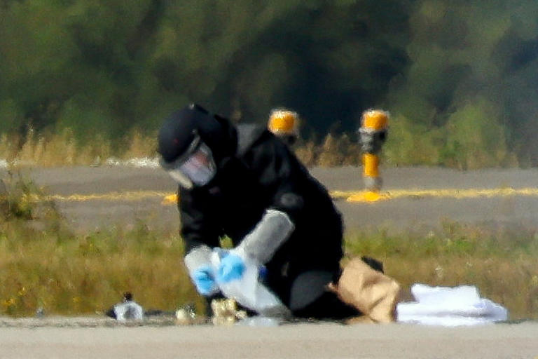A police investigator works on the tarmac with a robot capable of defusing explosives (Reuters)