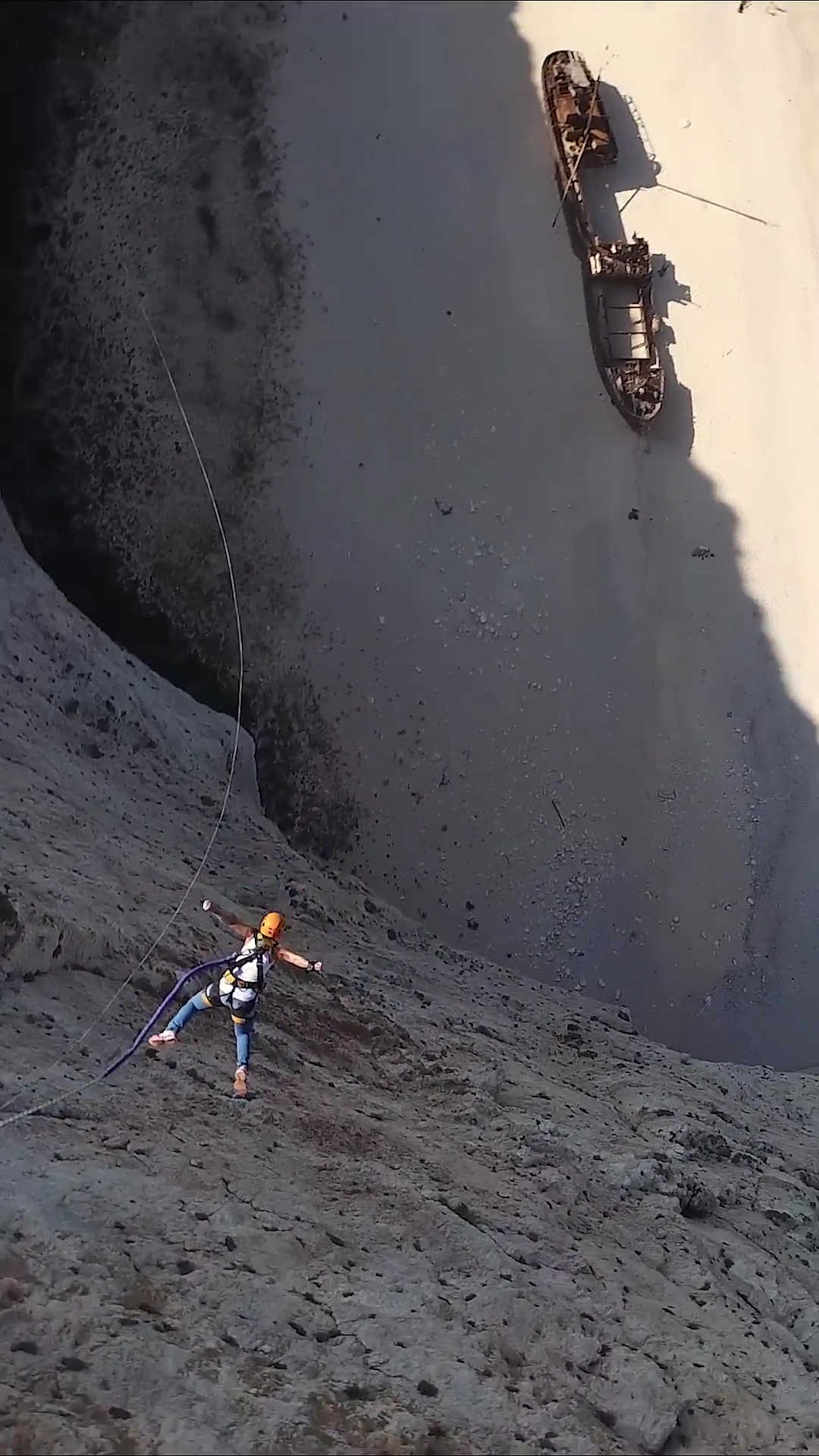 Extreme rope swing drop near rocky beach coastline