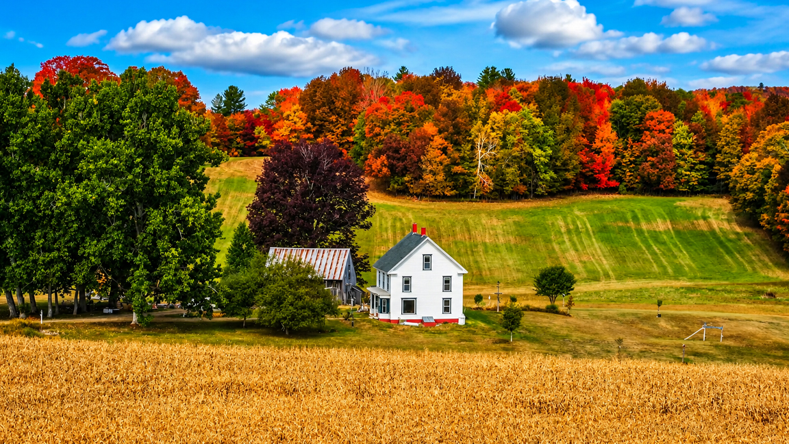 Peaceful farmhouse among fields and colorful autumn trees