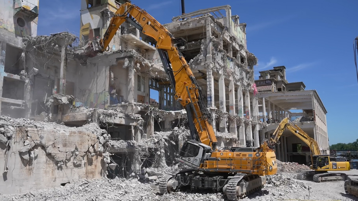Giant high reach excavator dismantling a multi-story structure