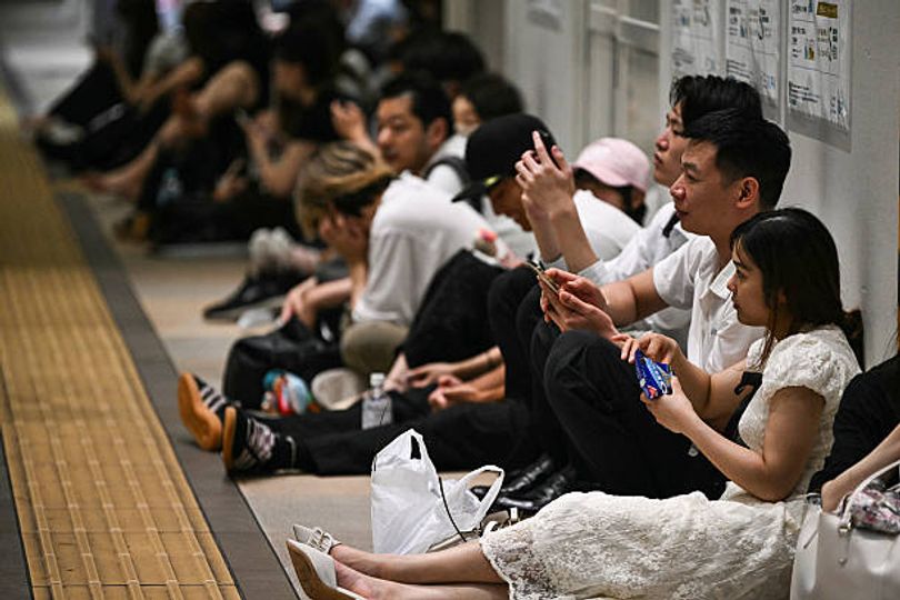 Stranded passengers sit on the floor at Chiba Metro Station in Chiba on August 13, 2026