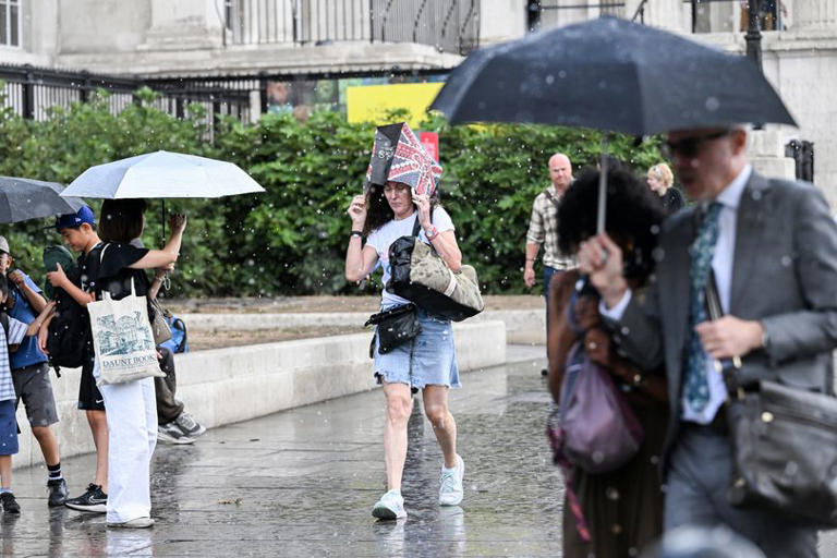 People carry shopping bags over their heads and umbrellas
