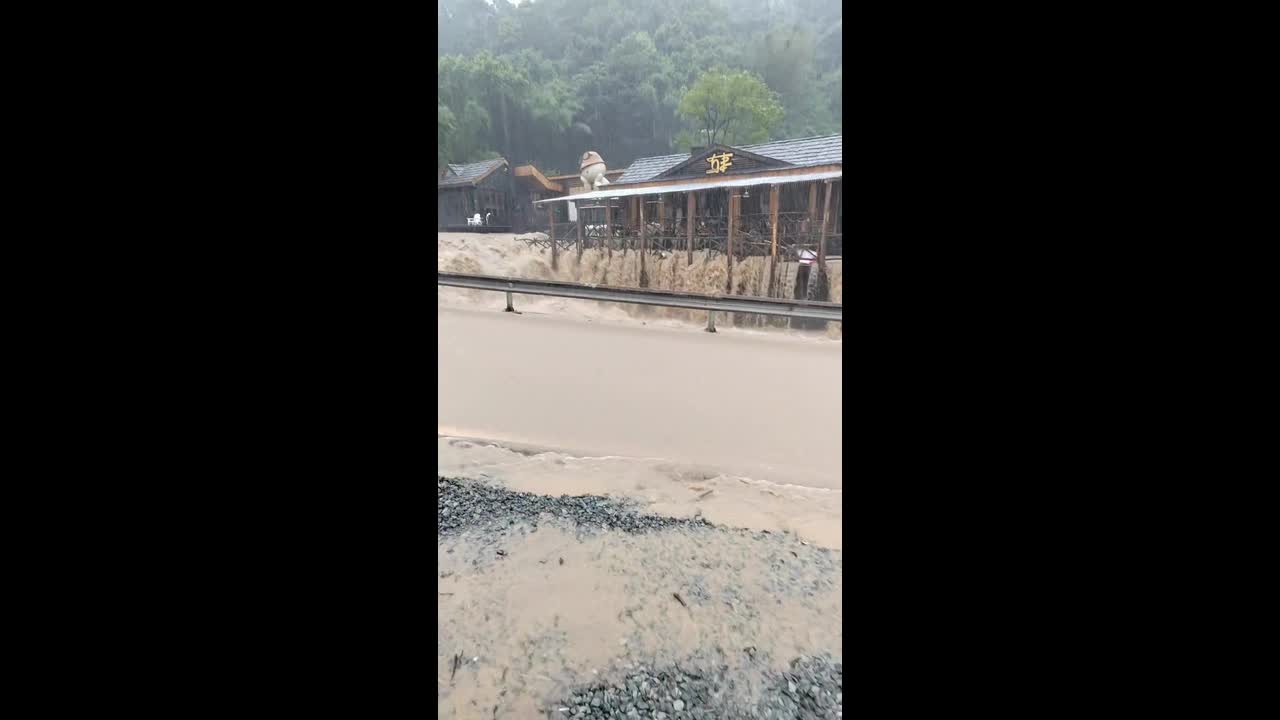 Turbulent river overflows onto road and surrounding area in Cangnan, China
