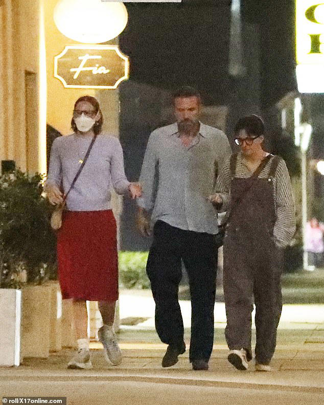 Violet wore a light-colored cardigan, knee-length red skirt, and sneakers. She wore a white KN95 mask, which she often wears as the result of a post-viral condition she suffered in 2019