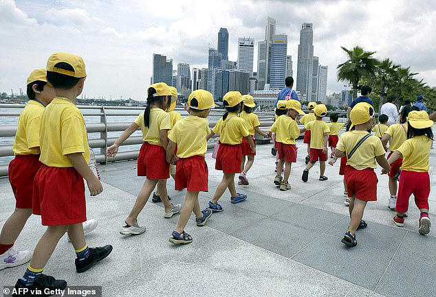 Singapore will pay parents around £40,000 for each child they have in a bid to reverse the country's plunging birth rate (Pictured: Children walk at the Singapore River waterfront in 2004)