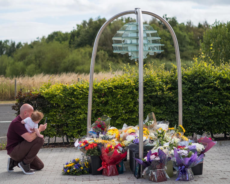 A father and daughter pay their respects as floral tributes are left at Cleveland police central headquarters memorial garden in Hemlington. Photograph: Ian Forsyth/Getty Images