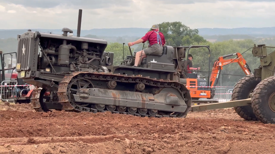 Vintage crawler tractor pulling heavy equipment through deep dirt