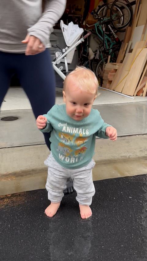Mom helps her baby enjoy playing in the rain