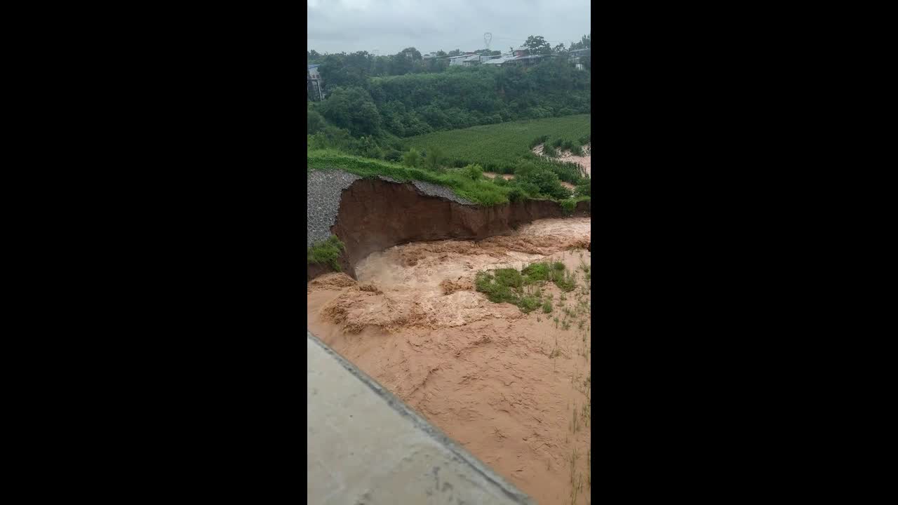 Hillside collapses as muddy floodwater rushes beneath bridge in Henan ...