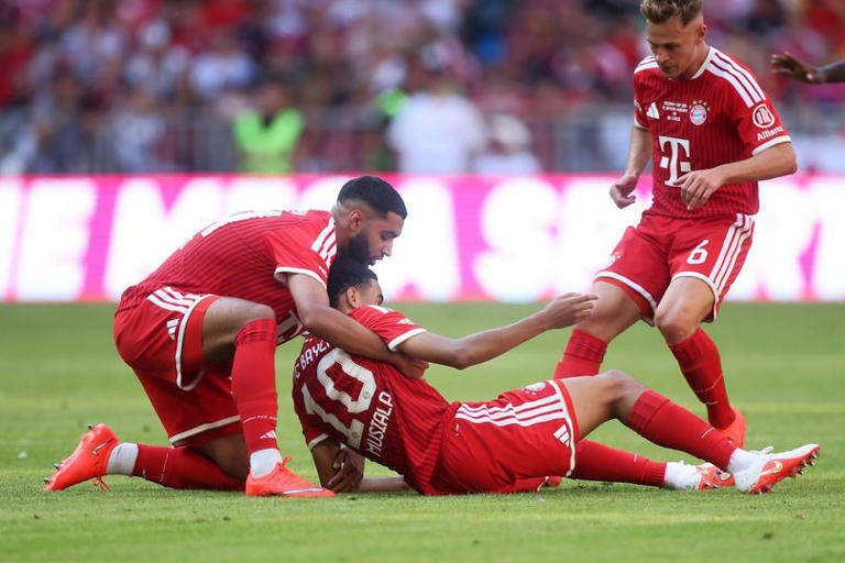 Ismael Saibari of Bayern Munich helps teammate Jamal Musiala during the Telekom Cup match between FC Bayern München and RB Leipzig.