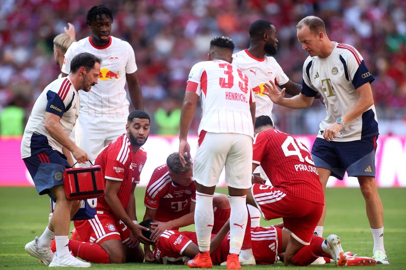 MUNICH, GERMANY - AUGUST 15: Jamal Musiala of Bayern Munich receives medical attention after sustaining an injury during the Telekom Cup match between FC Bayern München and RB Leipzig at Allianz Arena on August 15, 2026 in Munich, Germany. (Photo by Alex Grimm/Getty Images)