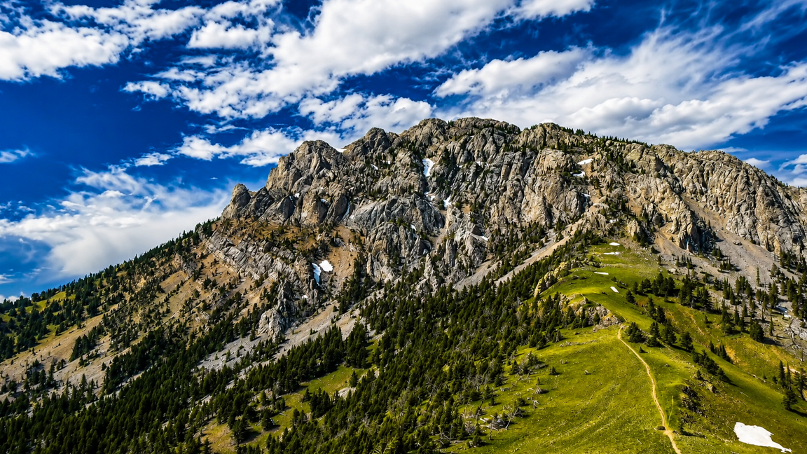 Rugged mountain ridge rises above a green alpine landscape
