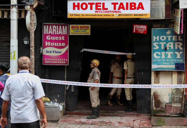 Firefighters stand at an entryway to a hotel where a fire broke out and killed several people, in Kolkata, India, August 19, 2026 (Reuters)