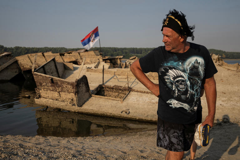 Zoran Lovric, a local fisherman, stands near a sunken German warship from the Second World War, exposed due to low Danube River levels near Prahovo, Serbia (Reuters)