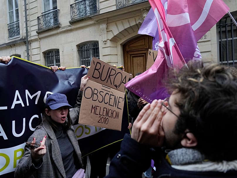 Nemesis founder Alice Cordier protests against a conference by Jean-Luc Mélenchon at Sciences Po in Paris on 22 April 2024, holding a sign reading "Burqa=obscene". (AP Photo/Thibault Camus)