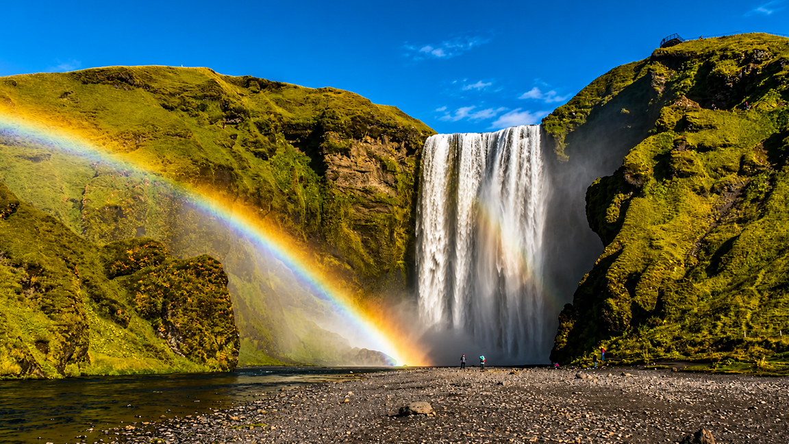 A rainbow arches across Iceland’s powerful Skógafoss waterfall