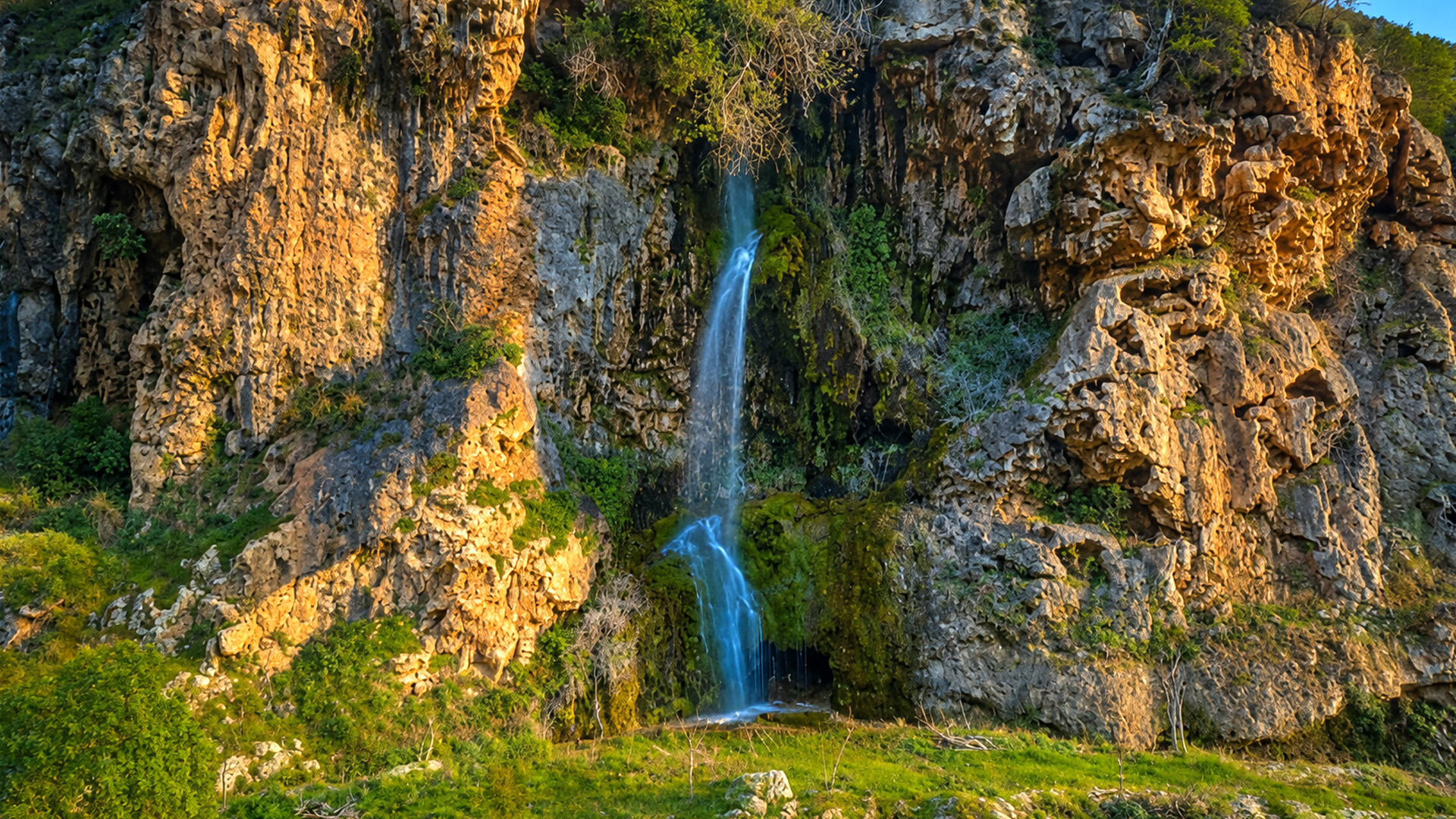 A waterfall cascading down Kermanshah’s towering rock cliffs