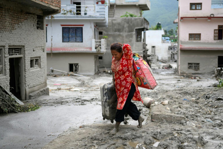 A woman salvages her belongings from her house heavily covered in mud following flash floods at Devighat in Nepal’s Nuwakot district on August 28, 2026