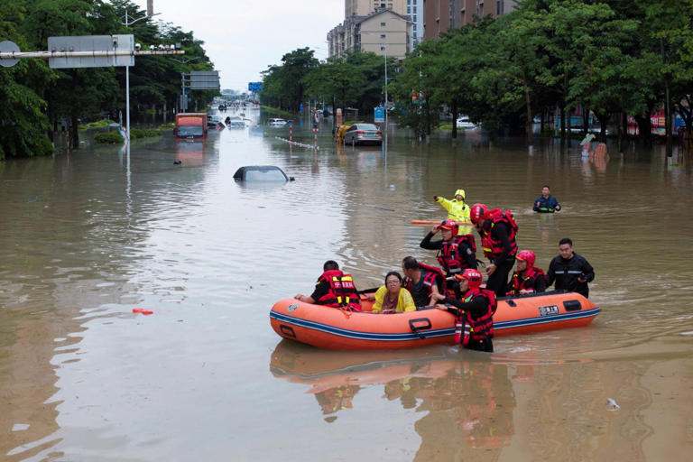 Emergency workers rescue residents in a boat on a flooded road in Putian city (Picture: Reuters)