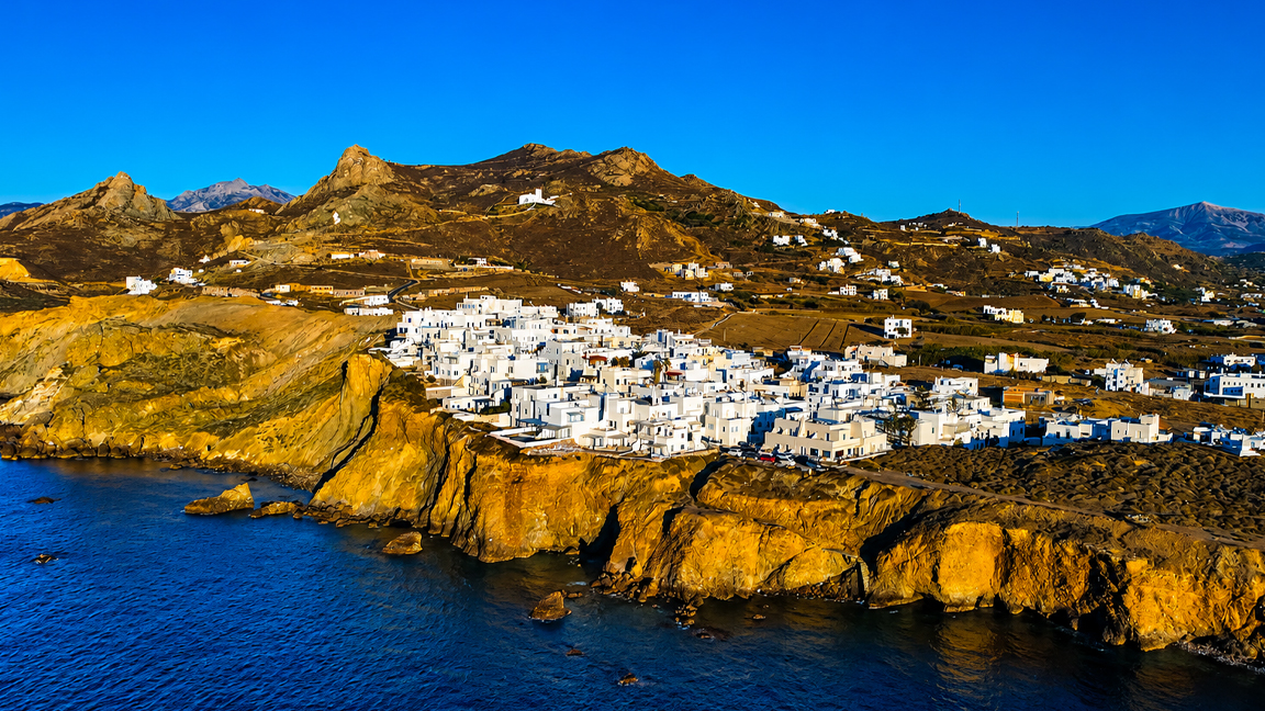 Whitewashed coastal village glows above the deep blue sea