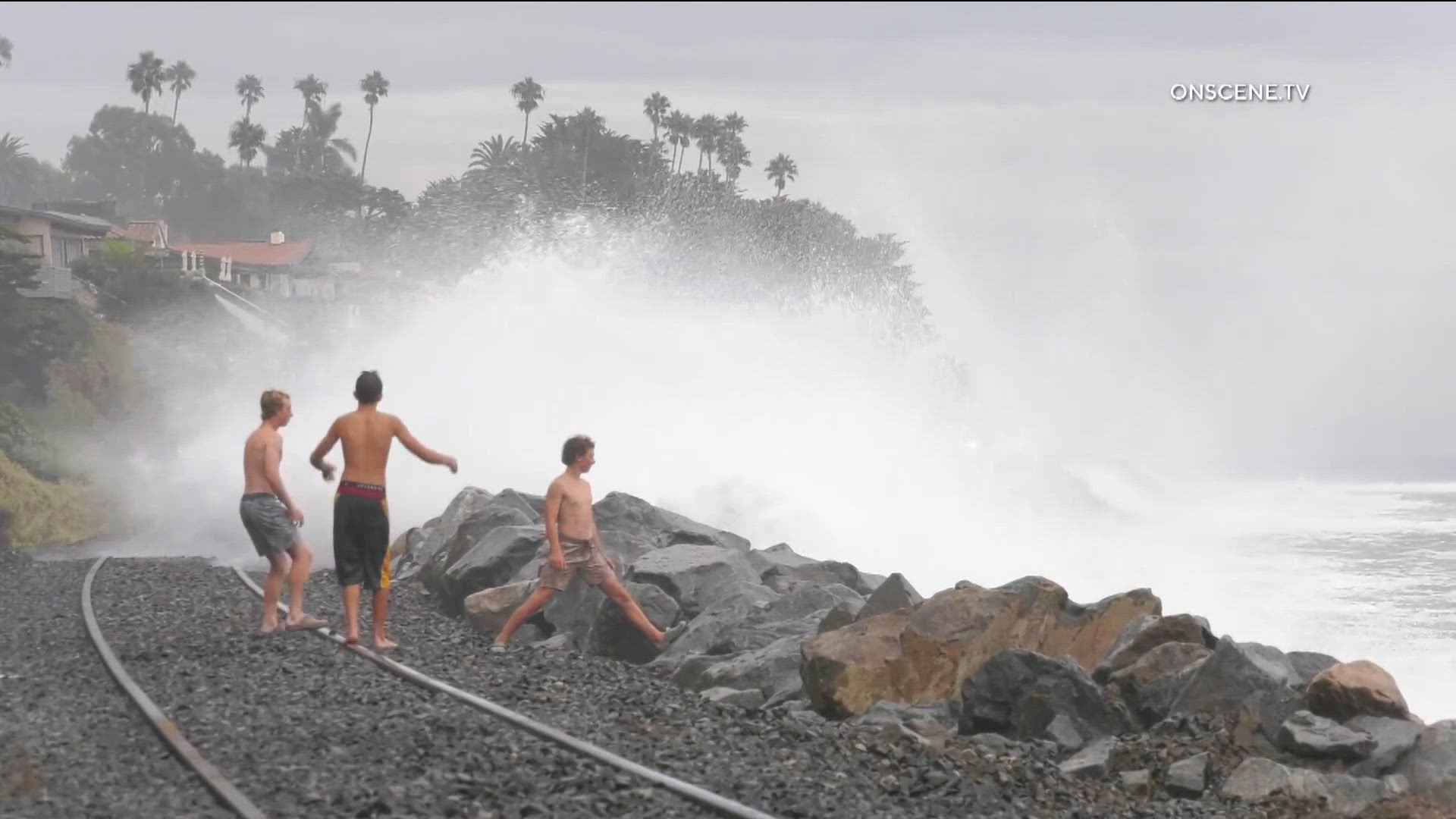 Powerful waves crash onto the shore near train tracks in Southern ...