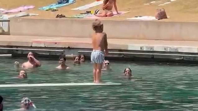 Crowd cheers for little boy as he braves diving board