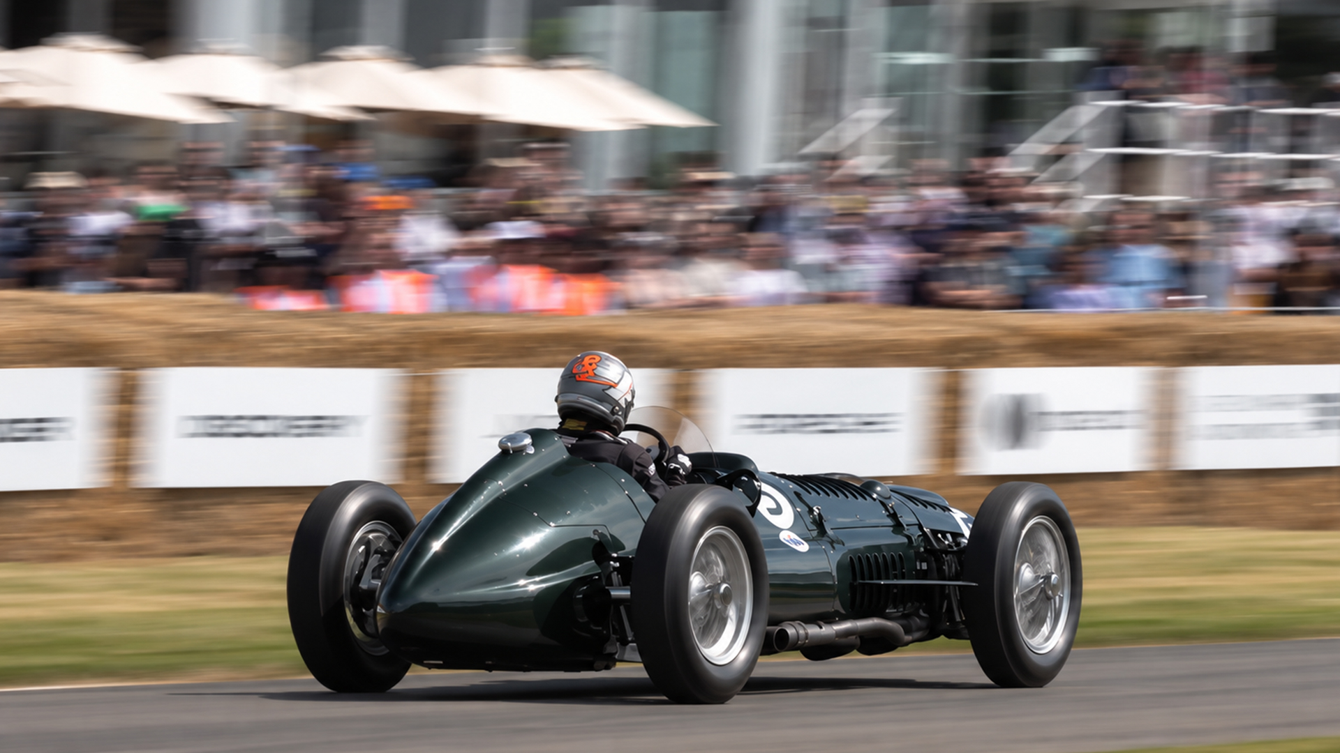 Vintage race car roars past a packed grandstand