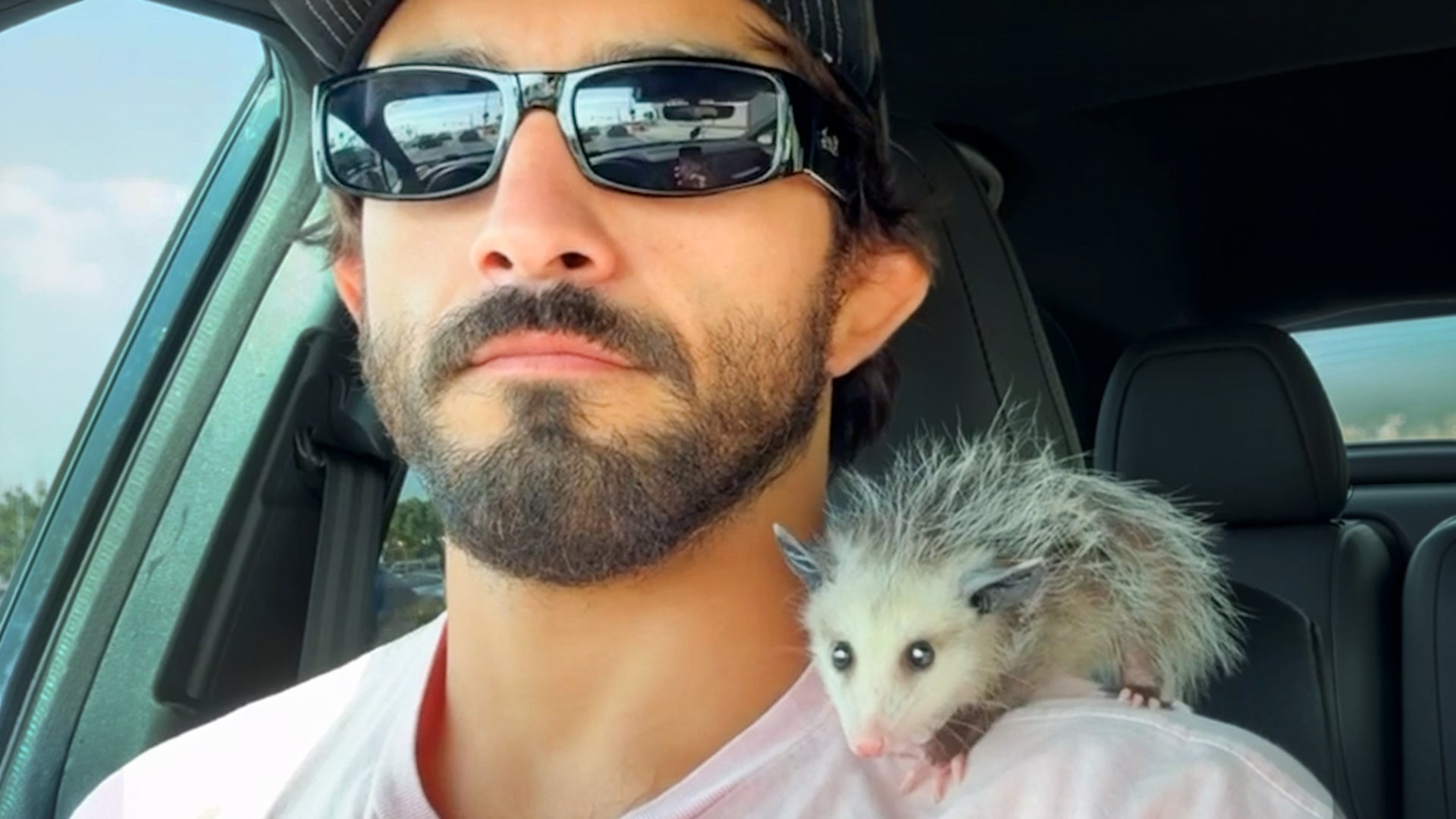 MMA fighter stops his bike for tiny opossum in the road