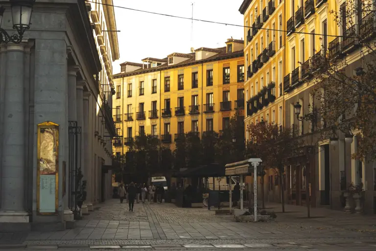 Cálido atardecer sobre una calle clásica de Madrid alineada con edificios históricos y árboles, capturando el encanto urbano.