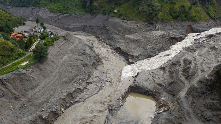 An aerial view shows a torrent of muddy water surging past houses and through the Trishuli River in the aftermath of flash floods (AFP/Getty)