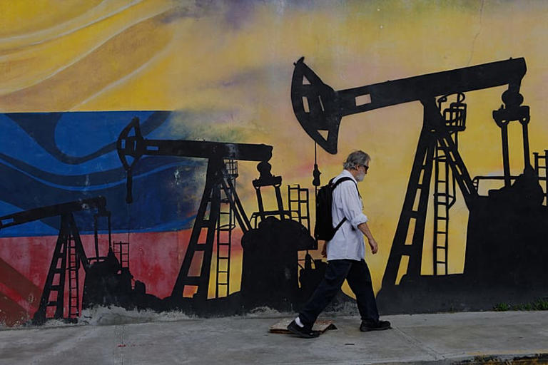 ARCHIVIO. Un pedone passa davanti a un murale con pozzi petroliferi a Caracas, Venezuela, 29 agosto 2026 AP Photo/Pedro Mattey