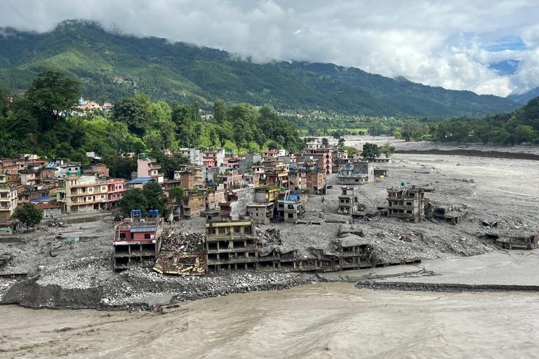 An aerial view shows a torrent of muddy water surging past houses and through the Trishuli River in the aftermath of flash floods at Trishuli Center in Nepal's Nuwakot district (AFP/Getty)