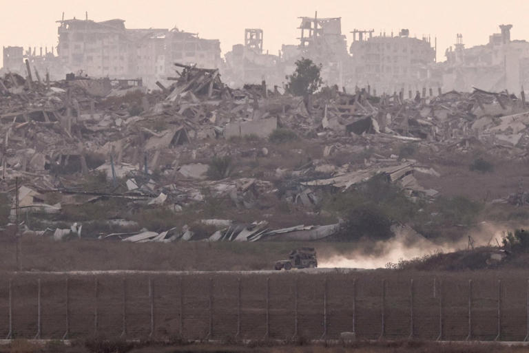 An Israeli military vehicle in Gaza against a backdrop of destroyed buildings.