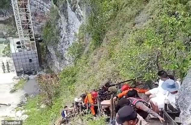 The base of the abandoned lift could be seen in the background as emergency crews and tourists carried Ms Cronin's body back up the treacherous track