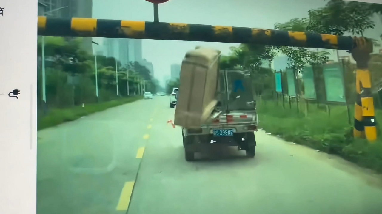 Oversized box falls from mini-truck after hitting height barrier in Hunan