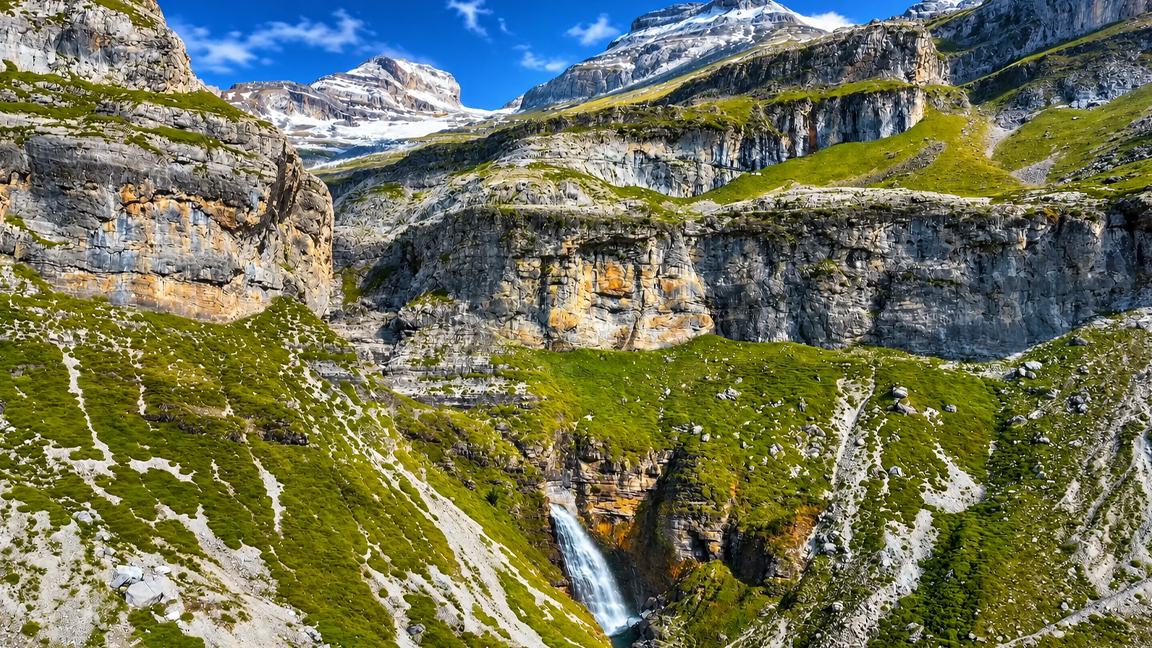 Hidden waterfall beneath layered alpine cliffs