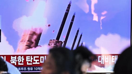 People sit near a television screen showing a news broadcast with file footage of a North Korean missile test at a train station in Seoul.