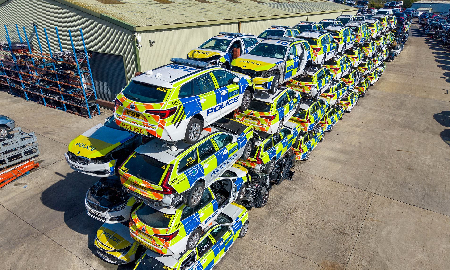 Dozens of smashed police vehicles line scrapyard with wall of wrecks ...